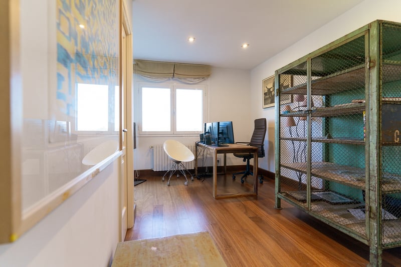 Bureau à domicile avec parquet, bureau à double écran et une armoire grillagée en métal vert vintage.