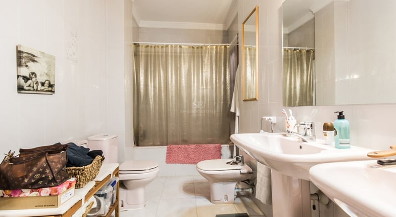 Salle de bain avec double vasque, toilettes, bidet et baignoire avec rideau doré.