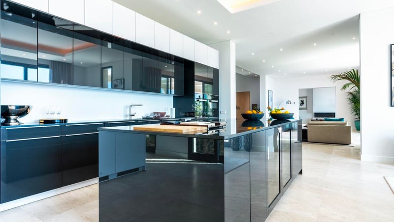Cuisine de luxe à aire ouverte avec des armoires noir brillant, un grand îlot central et un design contemporain.