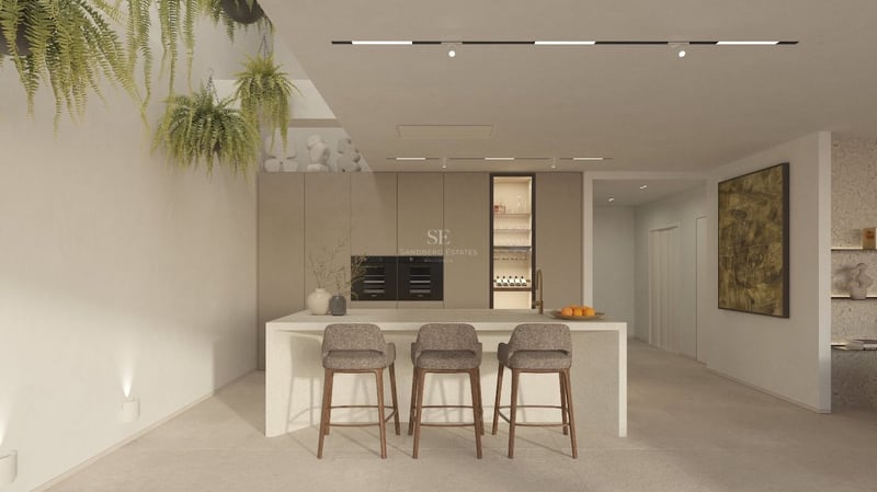 Cuisine moderne avec îlot en pierre, tabourets, plantes suspendues et appareils intégrés sur tons beiges.