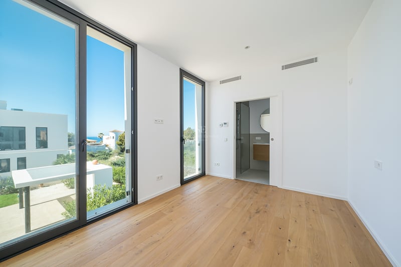 Chambre lumineuse vide avec parquet en bois clair, grandes fenêtres et accès à une salle de bain privée.