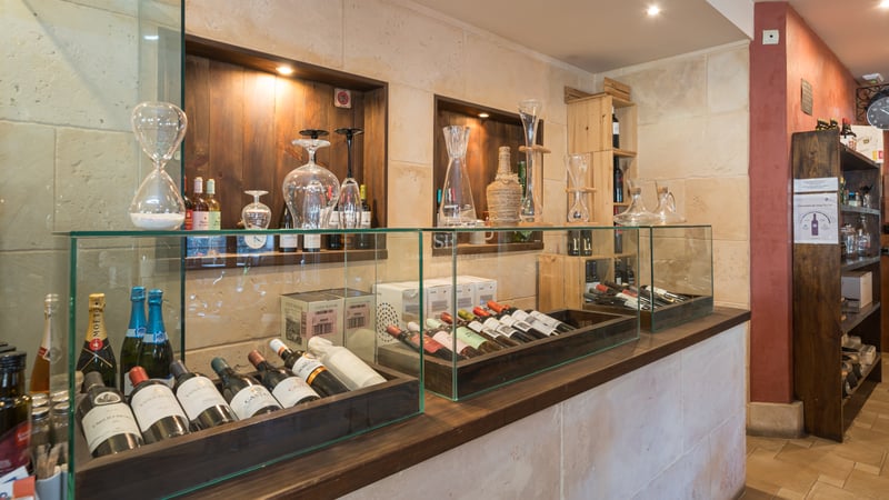 Cave à vin haut de gamme avec murs en pierre, vitrines en verre et étagères en bois foncé.