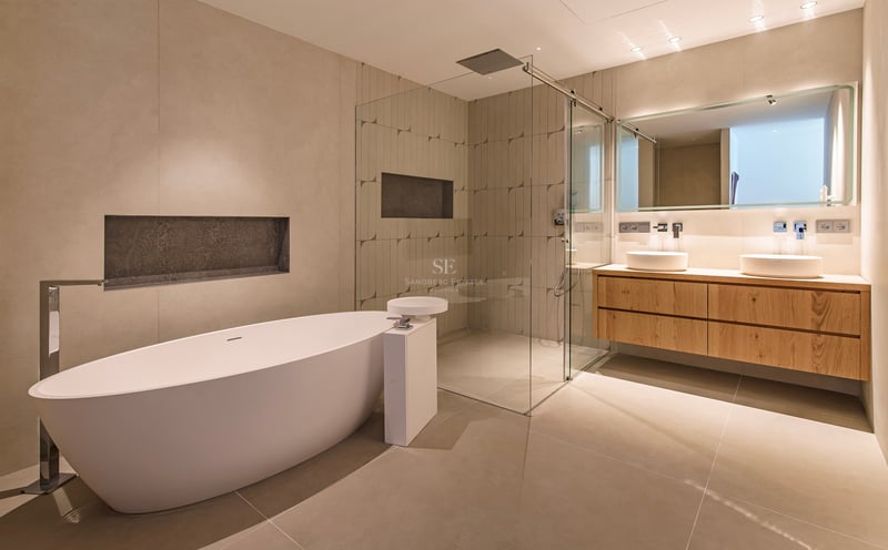 Salle de bains moderne avec baignoire îlot blanche, douche à l'italienne vitrée et double vasque en chêne.