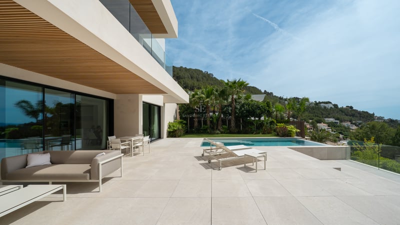 Terrasse de villa de luxe avec une grande piscine, du mobilier contemporain et des vues panoramiques sur la côte.