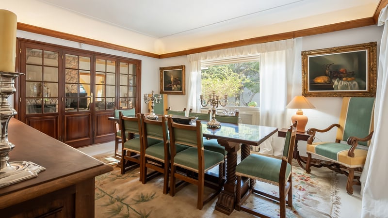 Salle à manger traditionnelle avec table en bois foncé, chaises vertes, candélabres en argent et tableaux classiques.