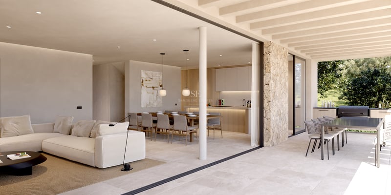 Vaste salon intérieur avec canapé blanc s'ouvrant sur une terrasse extérieure avec coin repas et cuisine.
