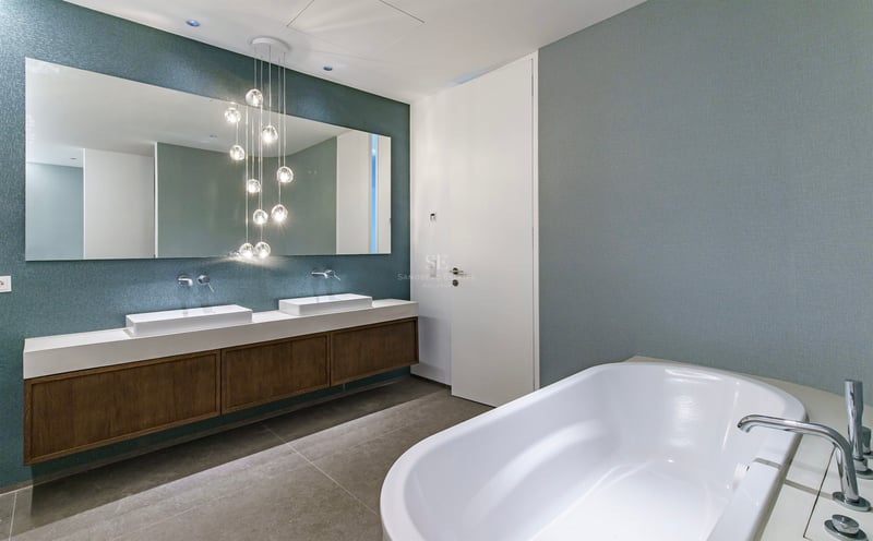 Salle de bain de luxe avec baignoire blanche, meuble double vasque en bois et suspensions boules en verre.