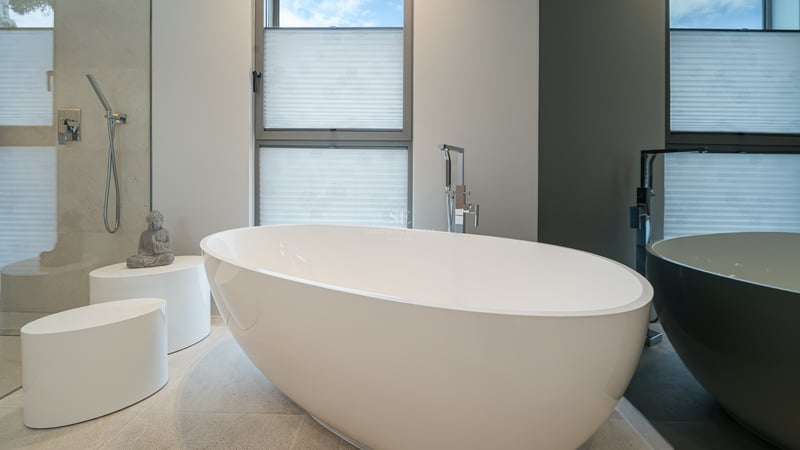 Salle de bain minimaliste avec baignoire îlot blanche, sol en pierre naturelle et douche à l'italienne.