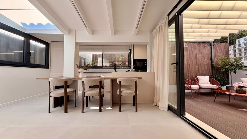 Salle à manger moderne avec table en bois et chaises design à côté d'une baie vitrée ouvrant sur une terrasse privée.