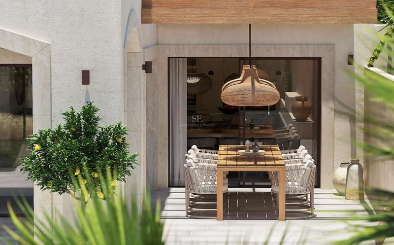 Table de repas en bois sur une terrasse en pierre naturelle avec chaises tressées et un citronnier en pot.