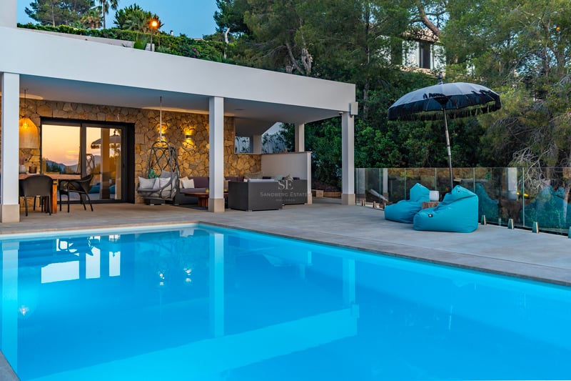 Grand salon avec baies vitrées, parquet clair, canapés beiges, tapis en laine, cheminée et vue panoramique sur la mer. Design moderne et lumineux.