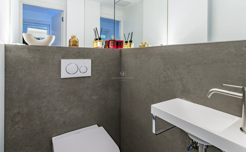 Salle d'eau minimaliste avec murs en grès cérame gris, lavabo suspendu blanc et grand miroir.