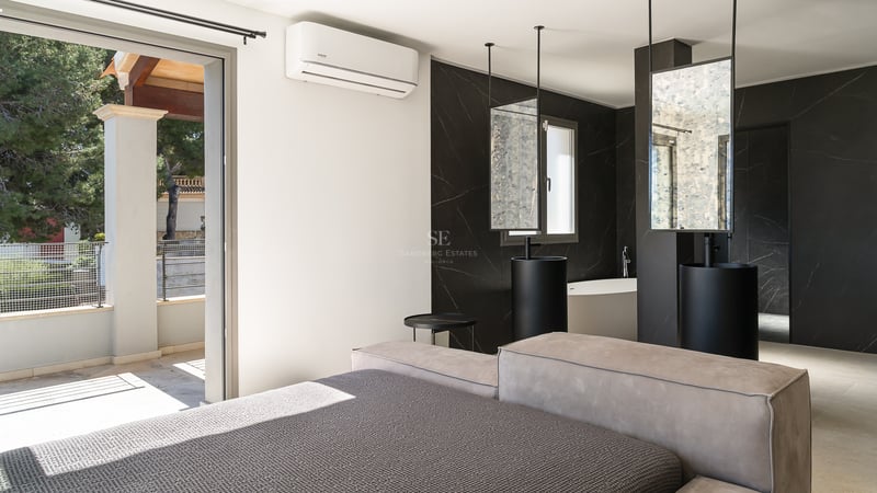 Chambre de luxe avec salle de bain ouverte en marbre noir, doubles vasques colonnes et accès terrasse.