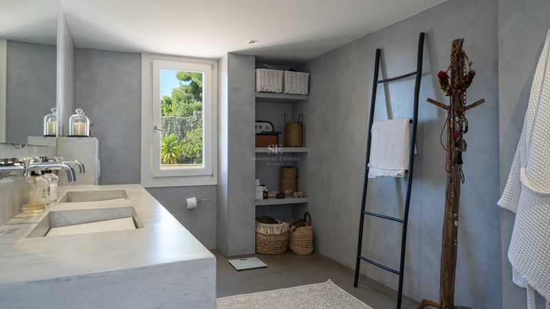 Salle de bain moderne avec double vasque en microciment gris, étagères ouvertes et échelle porte-serviettes noire.