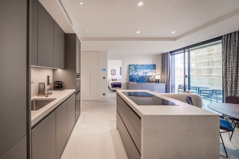 Cuisine contemporaine avec îlot en pierre, armoires anthracite et baies vitrées donnant sur une terrasse.
