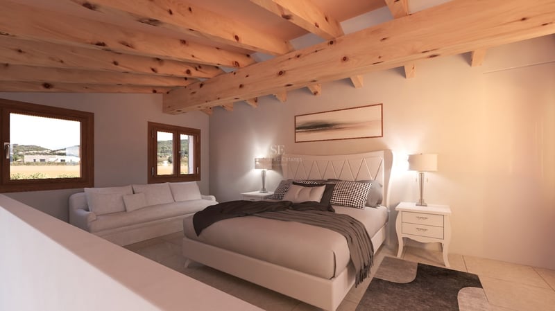 Chambre avec grand lit, poutres en bois, canapé blanc et fenêtres donnant sur la campagne.