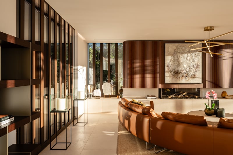 Salon moderne avec canapé en cuir courbé, mur en lattes de bois, cheminée linéaire et lumière naturelle.