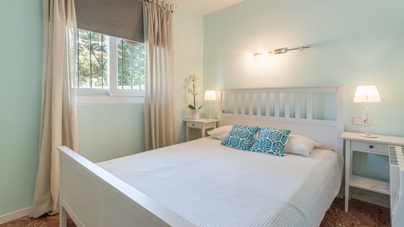 Chambre vert menthe avec lit en bois blanc, tables de chevet assorties et sol en carrelage traditionnel.