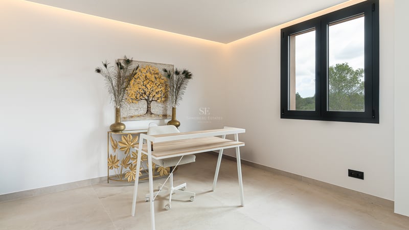 Un espace bureau moderne avec un bureau blanc, des œuvres d'art dorées et un éclairage LED indirect.
