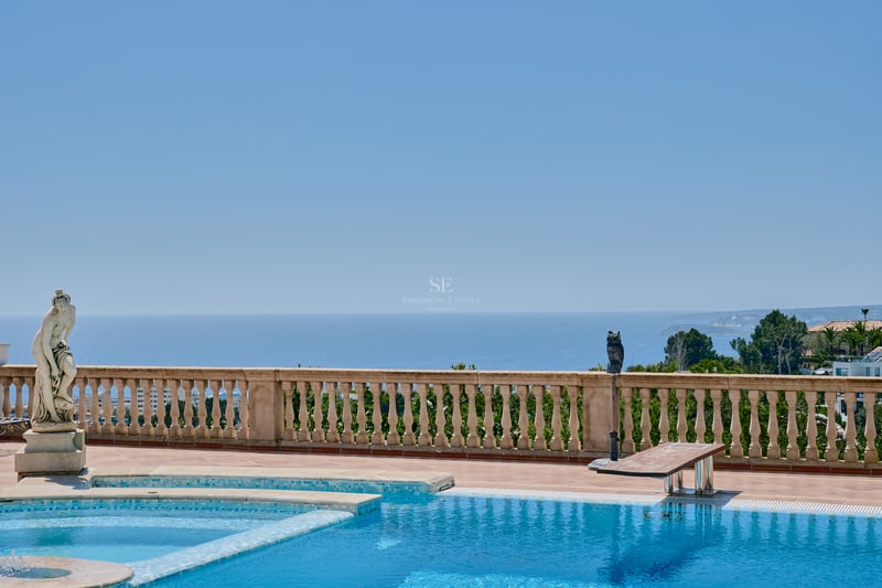 Grande piscine extérieure avec balustrade en pierre classique et statue dominant la mer Méditerranée.