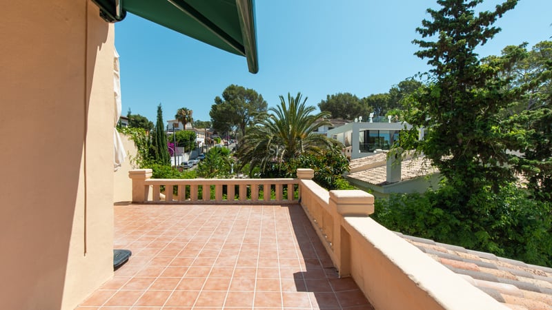 Terrasse baignée de soleil avec carrelage en terre cuite et balustrade classique surplombant la verdure méditerranéenne.