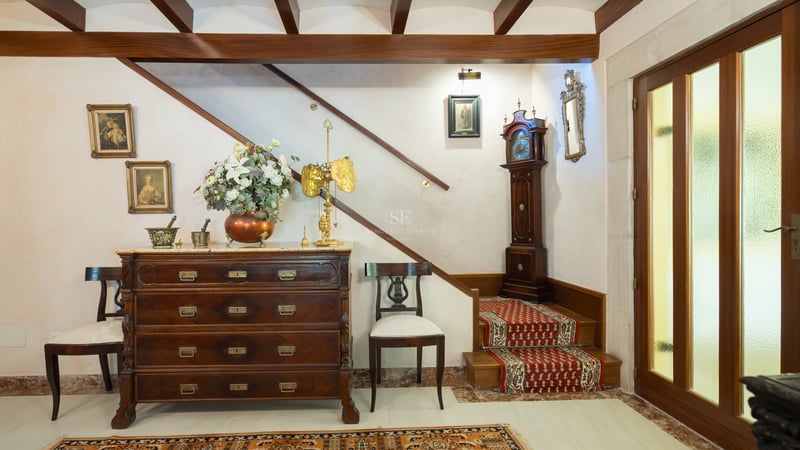 Entrée traditionnelle avec commode en bois sombre, horloge de parquet et escalier avec tapis rouge.