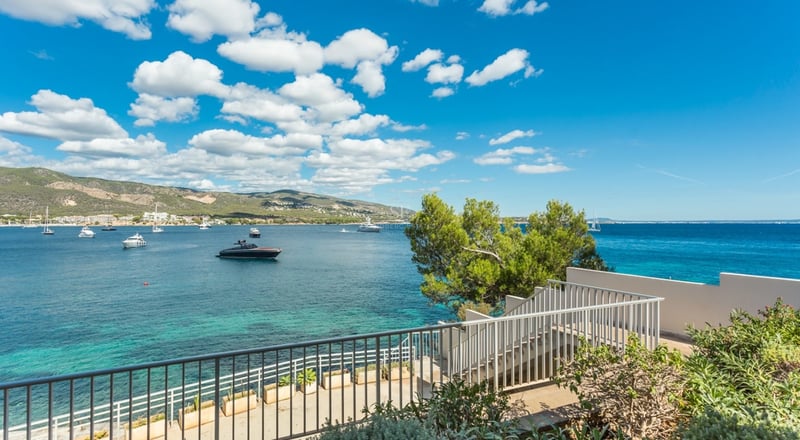 Salon lumineux avec grandes baies vitrées, parquet clair et vue panoramique sur la mer. Mobilier moderne et élégant.
