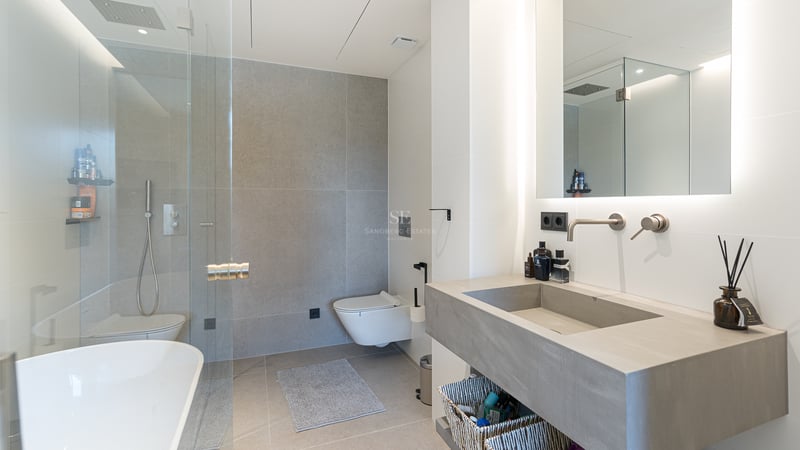Salle de bains contemporaine avec carrelage gris, douche à l'italienne, vasque intégrée et miroir rétroéclairé.