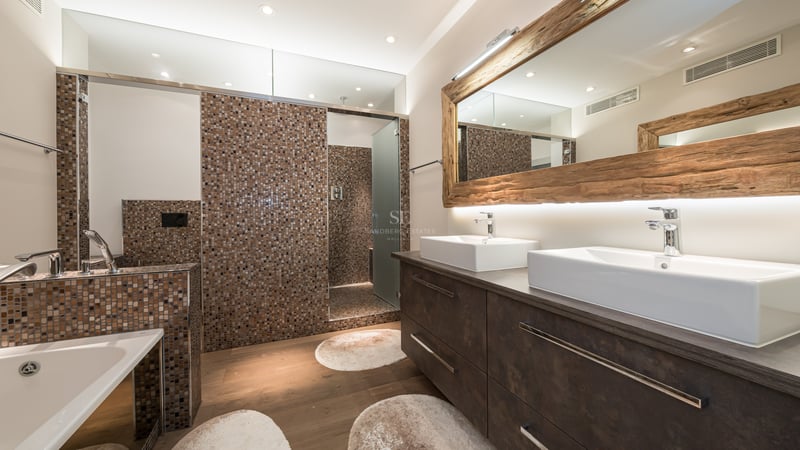 Salle de bains moderne avec double vasque, grand miroir encadré de bois brut et douche à l'italienne en mosaïque.