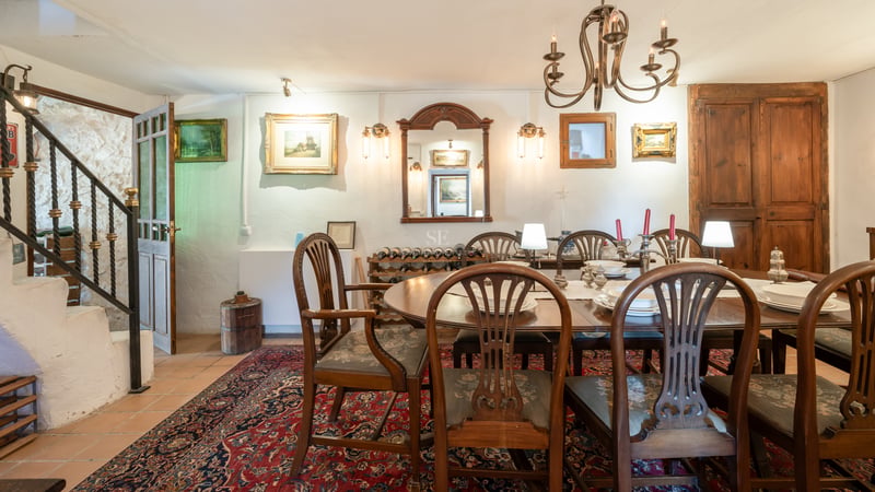 Espace dînatoire formel avec table ovale en bois, chaises de style et tapis oriental rouge.