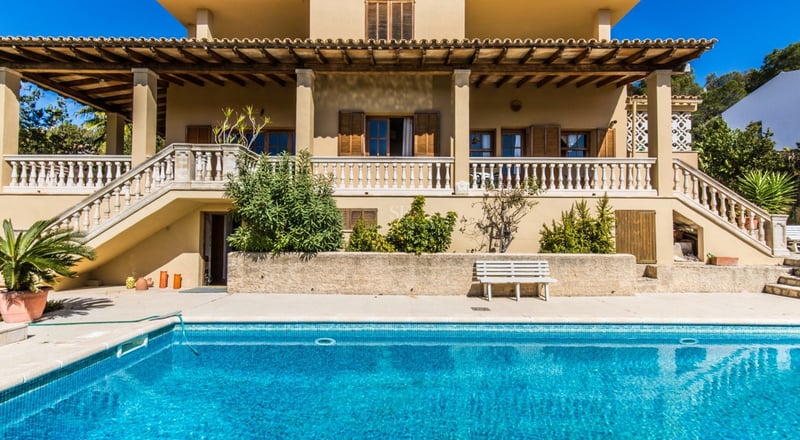 Villa de style méditerranéen avec une grande piscine bleue et une terrasse avec balustrade en pierre.