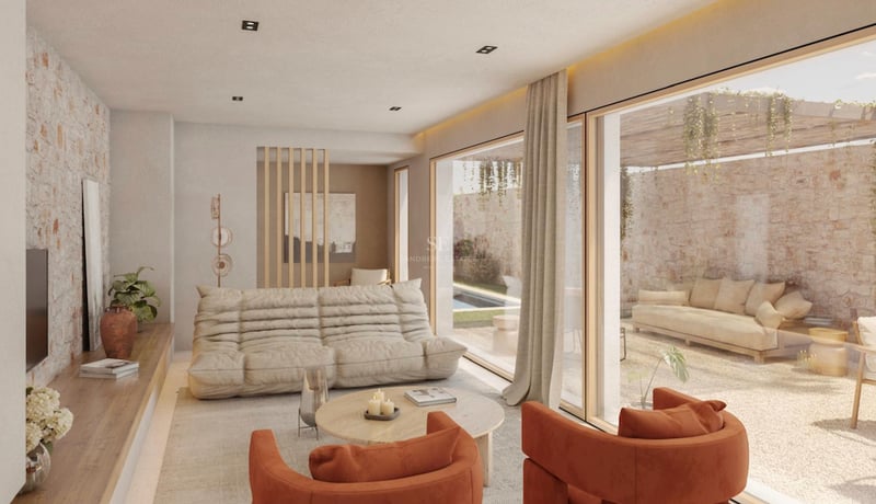 Salon moderne avec canapé beige, fauteuils en velours orange et grandes baies vitrées ouvrant sur une terrasse en pierre.