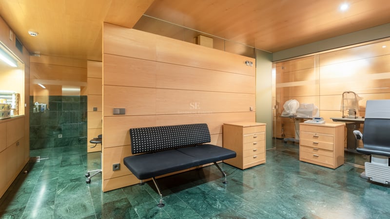 Interior with green marble flooring, light wood wall panels, a black bench, and professional consultation equipment.