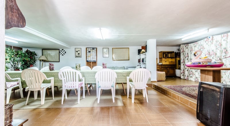 Grande table à manger avec chaises blanches dans une pièce carrelée au décor traditionnel.