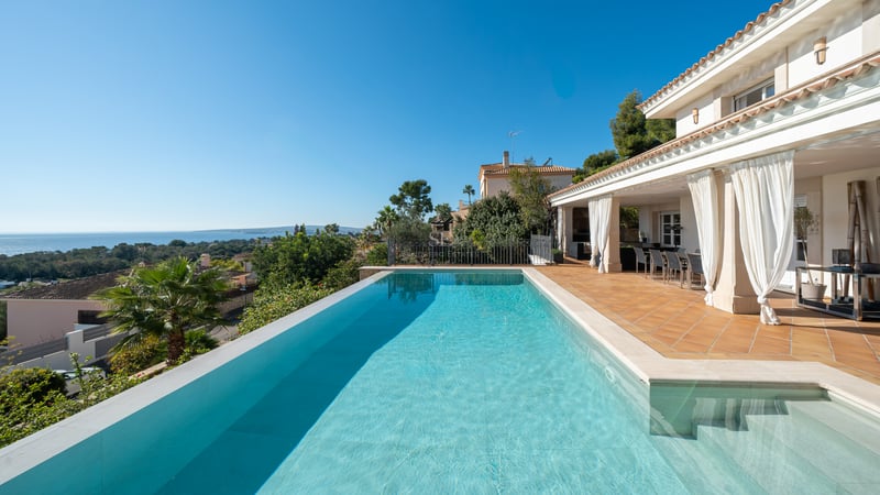 Piscine à débordement sur une terrasse en terre cuite surplombant la mer Méditerranée et le littoral.