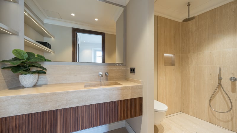 Modern bathroom featuring a travertine stone vanity with a fluted wood cabinet and a walk-in rain shower.