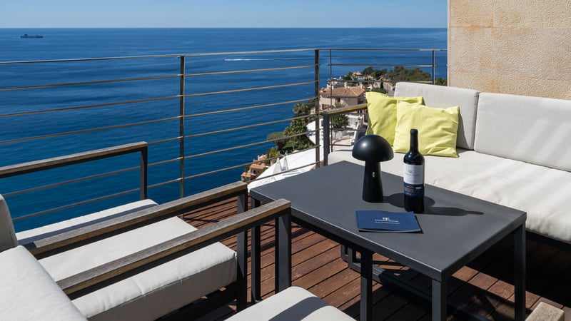 Terrasse moderne avec mobilier de salon et revêtement en bois surplombant la mer Méditerranée.