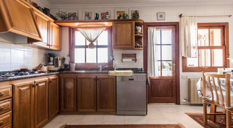 Cuisine lumineuse avec des meubles en bois chaleureux, des carreaux blancs et des plans de travail en granit.