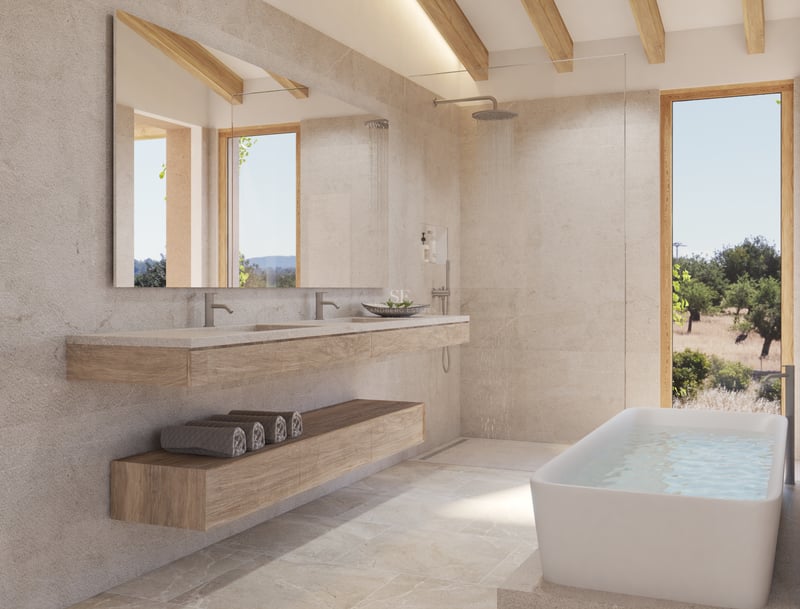 Salle de bains moderne en pierre naturelle avec baignoire îlot, double vasque en bois et vue sur des oliviers.
