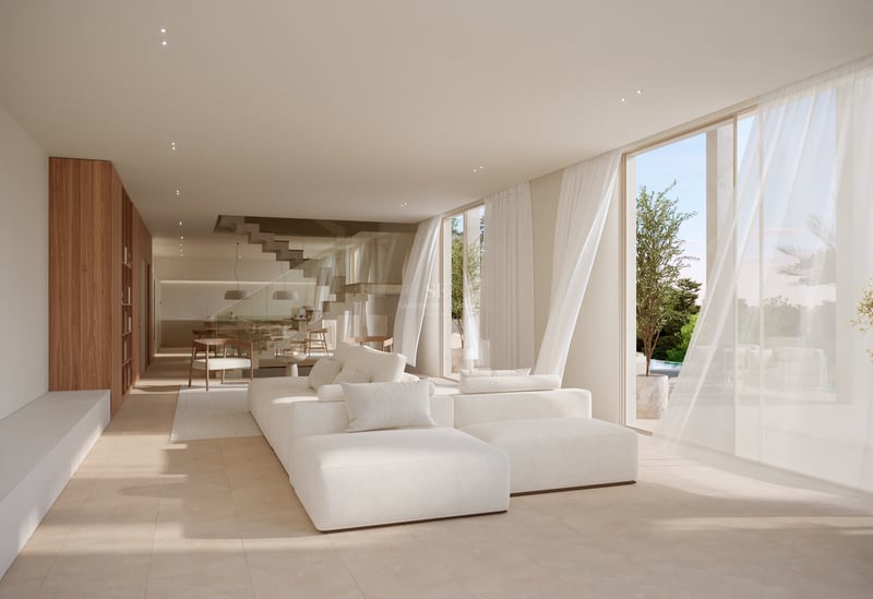 Salon lumineux avec grand canapé modulable blanc, baies vitrées et sol en pierre naturelle.