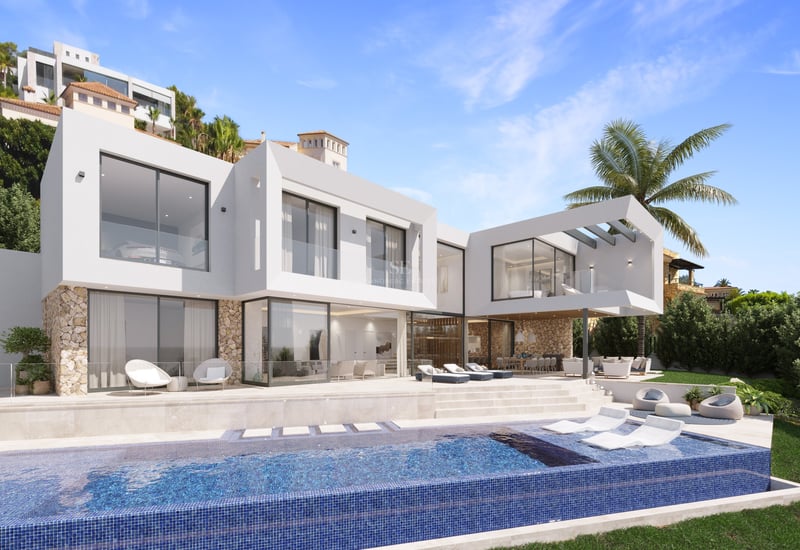 Villa moderne blanche avec piscine à débordement, chaises longues, garde-corps en verre et murs en pierre naturelle.
