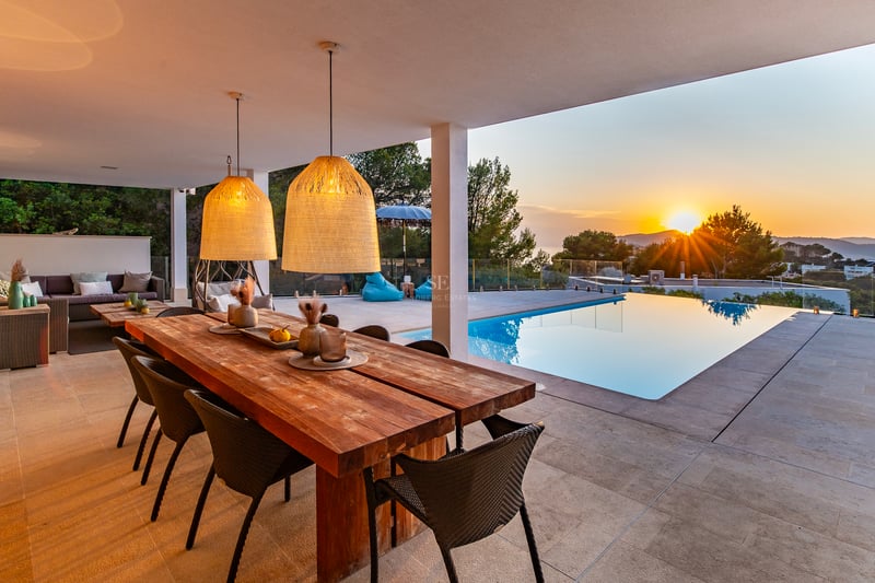 Vue extérieure d'une villa moderne avec piscine à débordement, terrasse, jardin luxuriant et grandes baies vitrées offrant une lumière naturelle.