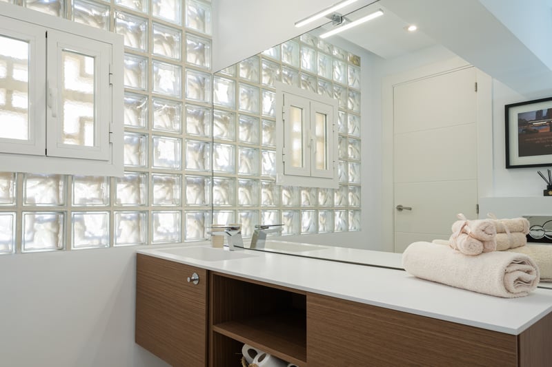 Salon spacieux avec baies vitrées offrant une vue panoramique sur la mer, parquet clair et mobilier moderne dans des tons neutres.