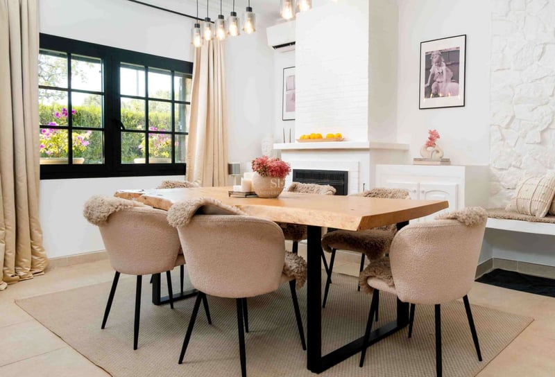 Salle à manger moderne avec table en bois naturel, chaises bouclées et cheminée blanche.