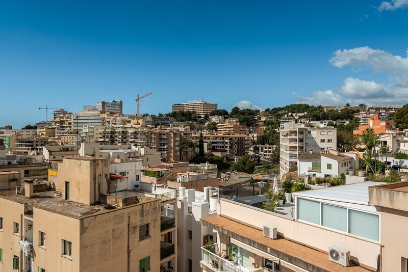 Vue panoramique sur les toits d'une ville méditerranéenne et ses immeubles sous un ciel bleu clair.