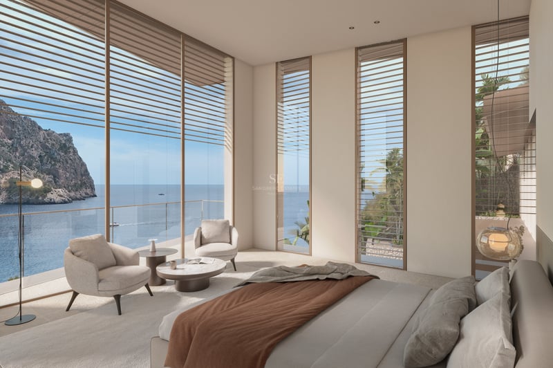 Chambre moderne avec baies vitrées donnant sur l'océan, fauteuils beiges et décoration épurée.