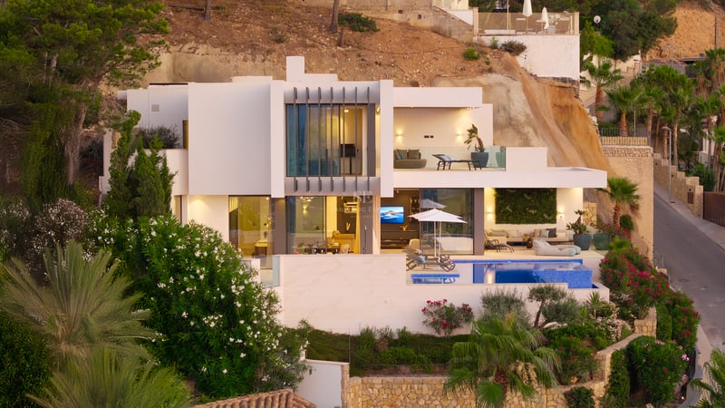Villa blanche moderne sur plusieurs niveaux avec piscine, terrasses et grandes baies vitrées nichée dans une colline.