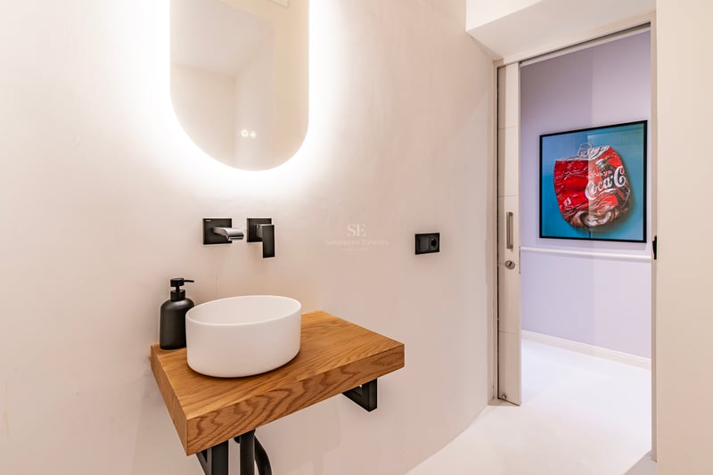 Vaste salon avec baies vitrées donnant sur la mer. Intérieur moderne avec mobilier élégant et lumière naturelle. Canapé beige, tapis clair, détails design.