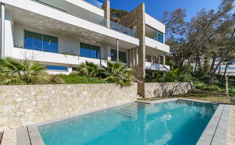 Villa moderne à plusieurs niveaux avec piscine turquoise, murs en pierre naturelle et balcons en verre.