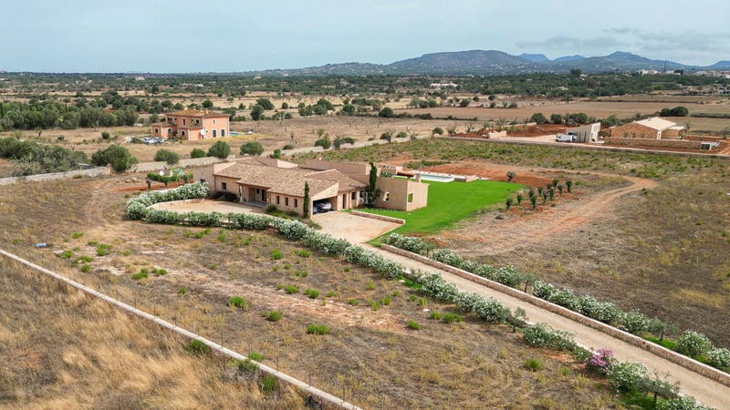 Vue aérienne d'une villa en pierre avec piscine et allée fleurie dans la campagne méditerranéenne.